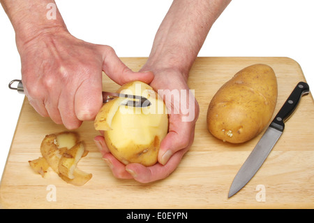 Nahaufnahme von ein paar Hände eine Kartoffel schälen, auf einem Holzbrett vor einem weißen Hintergrund Stockfoto