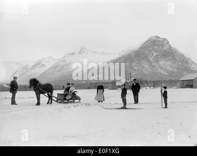 Ein historisches Foto aus der Zeit um 1890-1910, das Winteraktivitäten in Isfjorden, Norwegen, zeigt. Das Bild zeigt Einheimische, die Wintersportarten wie Skifahren und Schlittenfahrten ausüben, vor dem Hintergrund der malerischen norwegischen Landschaft in Møre og Romsdal. Stockfoto