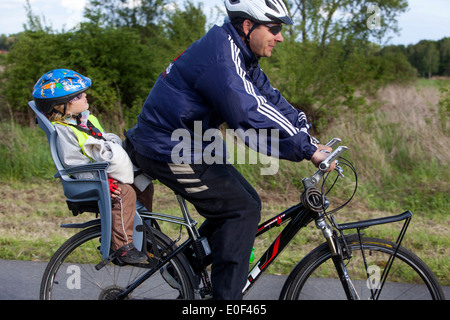 Mann und Kind fahren, Fahrradhelm, Radweg, Kind im Fahrradsitz Stockfoto