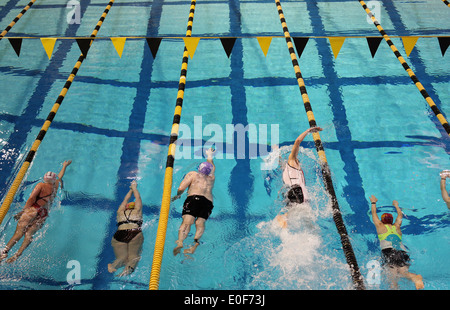 Menschen, die während eines Triathlon Wettkampfes Runden in einem Pool schwimmen. Stockfoto
