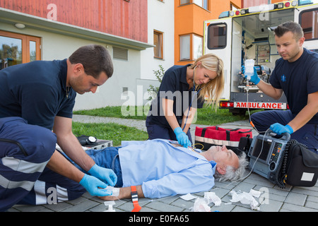 Sanitäter, einzuräumen, dass ers unbewusste senior Patienten liegend am Boden Stockfoto