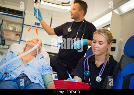 Paramedizinische Team Behandlung von unbewussten älterer Mann auf Bahre in Ambulanz Stockfoto