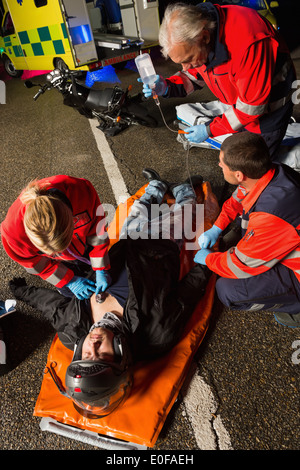 Paramedizinische Team helfen Verletzten Motorradfahrer Mann in der Nacht Stockfoto