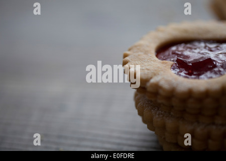 Erdbeermarmelade, herzförmige Linzer Kekse hautnah auf einem Holzbrett Stockfoto