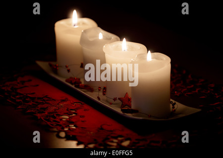 Brennende Kerze und Weihnachtsdekorationen auf Holztisch, auf dunklem Hintergrund Stockfoto