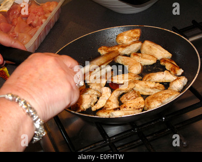 Frau, die Hähnchenteile in Pfanne braten Stockfoto