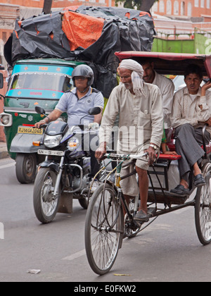 Eine Fahrradrikscha befördert Passagiere durch dichten Verkehr in das Zentrum von Jaipur, Indien Stockfoto