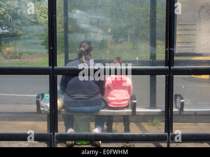 Rückansicht einer erwachsenen Frau und eines Kindes im Busunterstand. Stockfoto