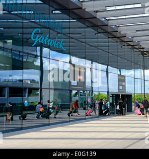 Gatwick Airport North Terminal Eingang & Schilder Reflexionen von Fluggästen mit Koffergepäck in reflektierendem Glas Crawley Sussex England UK Stockfoto