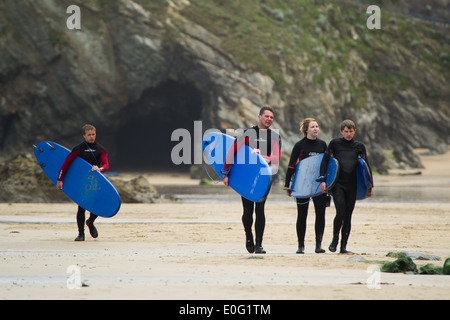 Vier Surfer Strandspaziergang hält ihre Surfbretter in Newquay, Cornwall, England. Stockfoto