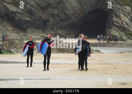 Vier Surfer Strandspaziergang hält ihre Surfbretter in Newquay, Cornwall, England. Stockfoto