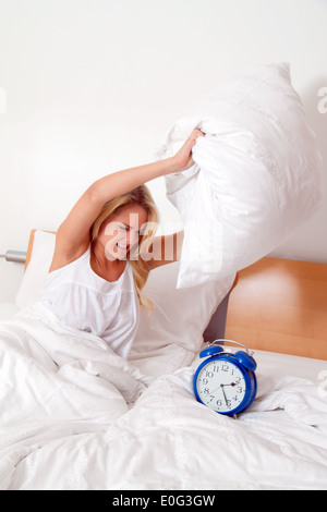 Junge Frau ist beim Aufwachen und steigt wütend. Alarm Clock (Uhr) Ringe., Junge Frau Aergert Sich Beim Sandbett Und Aufstehen. Stockfoto