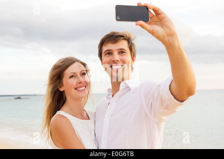 Glückliches junges Paar unter einem Selfie am Strand bei Sonnenuntergang Stockfoto