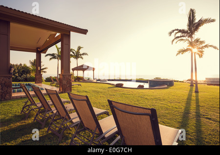 Schöne Heimat außen Terrasse Deck und Liegestühlen mit Blick auf den Sonnenuntergang auf Rasen Stockfoto