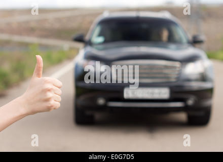 Frau, die ein Daumen aufgeben, wie sie aussieht, Trampen Stockfoto