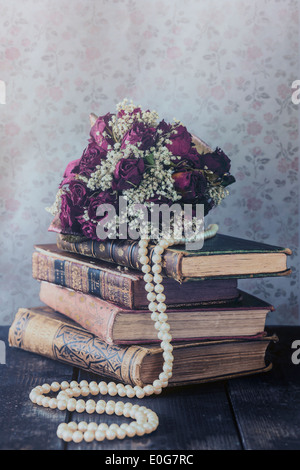 eine getrocknete rose Bouquet auf einem Stapel alter Bücher Stockfoto