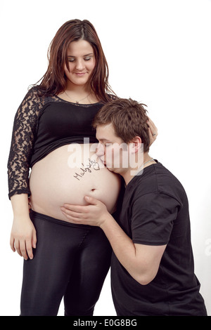 glückliches Liebespaar, schwangere Frau mit ihrem Ehemann, isoliert auf weißem Hintergrund, Mann küssen Bauch Stockfoto