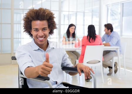 Geschäftsmann in Rollstuhl gibt Daumen hoch für Kamera Stockfoto