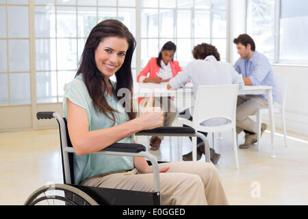 Attraktive Geschäftsfrau im Rollstuhl gibt Daumen hoch für Kamera Stockfoto