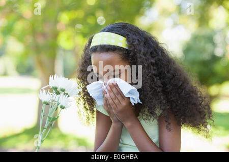 Junges Mädchen beim Blume saß und ihre Nase weht im park Stockfoto