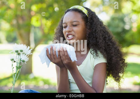 Junges Mädchen beim Blume saß und Niesen im park Stockfoto