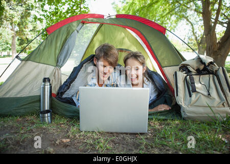 Süßes Paar liegen in ihrem Zelt mit laptop Stockfoto