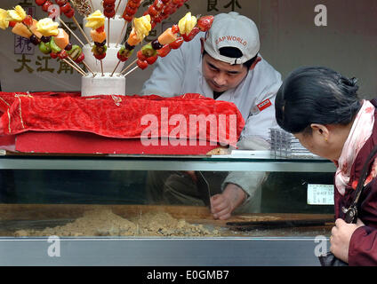 (140513)--Peking, 13. Mai 2014 (Xinhua)--Foto am 28. November 2013 zeigt eine Arbeitskraft Portion Erdnuss Candy für einen Kunden in Fuzhou, Fujian Provinz Südosten Chinas Hauptstadt.   Eines der beliebtesten Arten weltweit, chinesisches Essen ist berühmt für seinen Geschmack und Sorte, mit einer unvergleichlichen Auswahl an Essen Stile und Techniken, Zutaten und Gerichte. Die Geschichte des chinesischen Essens erstreckt sich über Tausende von Jahren zurück und hat sich geändert von Zeit zur Zeit und in jeder Region je nach Klima, Tradition und lokale Präferenzen. Chinesen sind stolz auf eine Vielzahl von Lebensmitteln zu essen Stockfoto