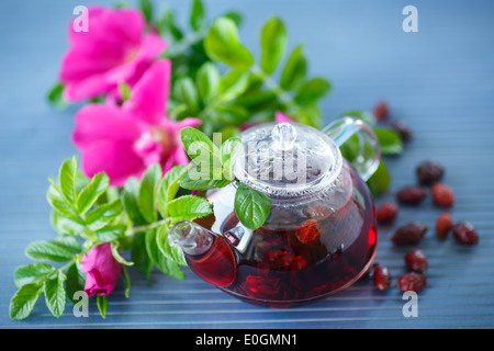 Hagebutten Tee mit Früchten und Blumen in einer Teekanne auf dem Tisch Stockfoto