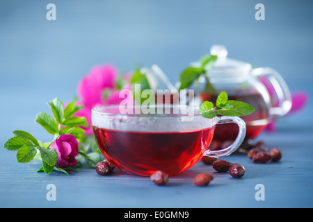 Hagebutten Tee mit Früchten und Blumen in einer Teekanne auf dem Tisch Stockfoto