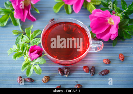 Hagebutten Tee mit Früchten und Blumen in einer Teekanne auf dem Tisch Stockfoto