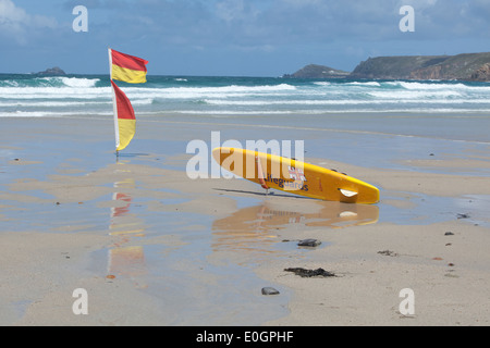 Rettungsschwimmer Surfbrett und Warnflaggen an einem leeren Strand bei Sennen Cove Cornwall Stockfoto