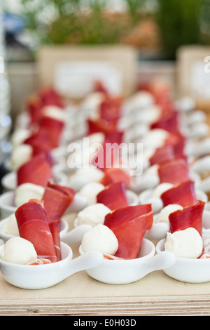 Nahaufnahme von Schinken und Kugel geformt Mozzarella Käse Häppchen in Reihen von kleinen weißen Schüsseln Stockfoto