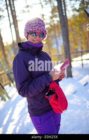 Junge attraktive Frau mit Mobiltelefon im Skigebiet pyhä, Lappland Stockfoto