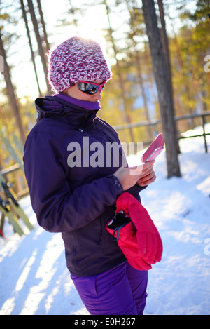 Junge attraktive Frau mit Mobiltelefon im Skigebiet pyhä, Lappland Stockfoto