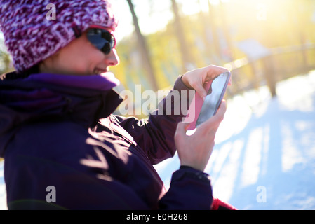 Junge attraktive Frau mit Mobiltelefon im Skigebiet Pyhä, Lappland Stockfoto