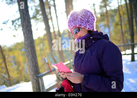 Junge attraktive Frau mit Mobiltelefon im Skigebiet Pyhä, Lappland Stockfoto