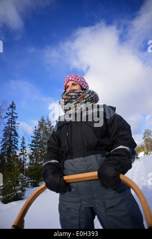 Junge Frau fahren Schlitten. Wüste husky Hundeschlitten taiga Tour mit bearhillhusky in Rovaniemi, Lappland, Finnland Stockfoto