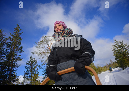 Junge Frau fahren Schlitten. Wüste husky Hundeschlitten taiga Tour mit bearhillhusky in Rovaniemi, Lappland, Finnland Stockfoto