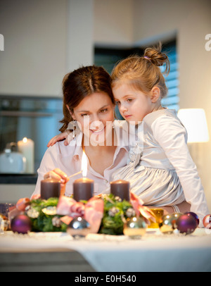 Mutter und Tochter (4 Jahre) Beleuchtung Kerze auf einem Adventskranz, Steiermark, Österreich Stockfoto