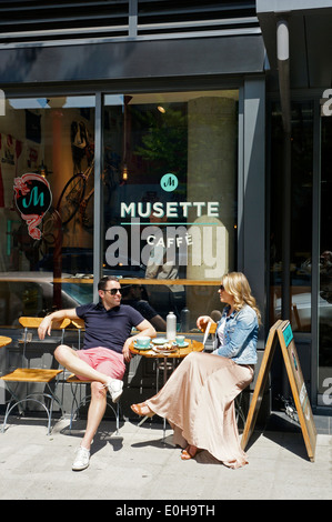 Entspannt auf der suche Mann und Frau außerhalb der Musette Caffe auf Pender Street in Chinatown, Downtown Eastside, Vancouver, BC, Kanada Stockfoto