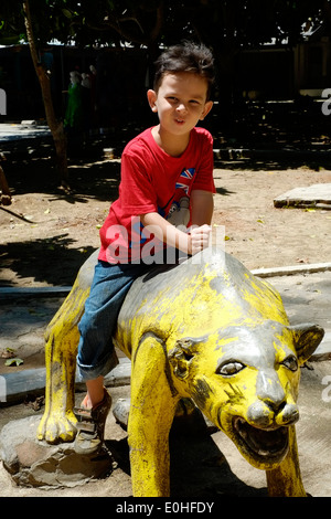 kleiner Junge reitet auf Skulptur von dem Strand und Meer bei Balekambang Ost-Java-Indonesien Stockfoto