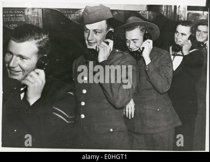 Auf diesem Foto werden Soldaten verschiedener Militärangehörigkeiten, einschließlich der Royal Australian Air Force und der U.S. Army, aufgenommen, die während des Zweiten Weltkriegs in Melbourne 1942 mit ihren Freundinnen telefonierten. Es zeigt einen persönlichen Moment inmitten der Kriegsanstrengungen. Stockfoto