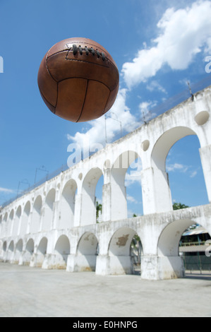 Vintage braun Ball Fußball fliegen in den Himmel in Arcos da Lapa Bögen Rio De Janeiro Brasilien Stockfoto