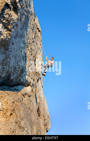 Extreme Klettern, Mann auf natürliche Mauer mit blauem Himmel. Stockfoto