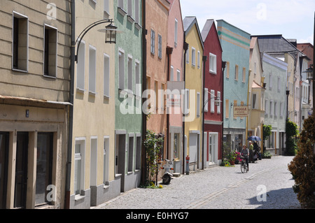 Ein Radfahrer reiten in einer Straße mit Kopfsteinpflaster, die von bunten dreistöckigen Gebäuden in einer Stadt an der Donau Fluss gesäumt, Deutschland Stockfoto