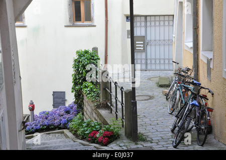 Fahrräder parken gegen eine Wand Blumen säumen eine Reihe von Schritten in Passau, Deutschland. Stockfoto