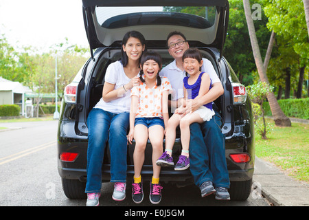 glückliche Familie sitzt im Auto und ihr Haus hinter Stockfoto