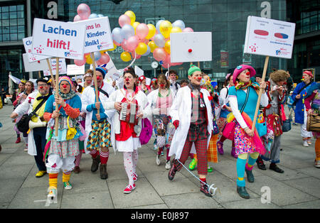 Berlin, Deutschland. 14. Mai 2014. Klinik-Clowns mit portest Anzeichen einer davon lautet "Lachen hilft" während einer Kundgebung von der Dachorganisation der Klinik-Clowns in der medizinischen Versorgung vor dem Hauptbahnhof in Berlin, Deutschland, 14. Mai 2014 zeigen. Clowns aus Hamburg, Bremen, Tübingen und Köln kam nach Berlin, um an der Rallye teilnehmen. Foto: Christoph Schmidt/Dpa/Alamy Live News Stockfoto