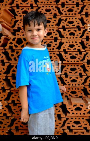 glückliche kleine Junge spielen neben einem Haufen Steine Stockfoto