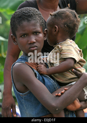 Eine haitianische Knabe und Kind warten in der Schlange vor einem Vertriebsstandort von Marines und Matrosen von der 22. Marine Expeditionary UNO eingerichtet Stockfoto